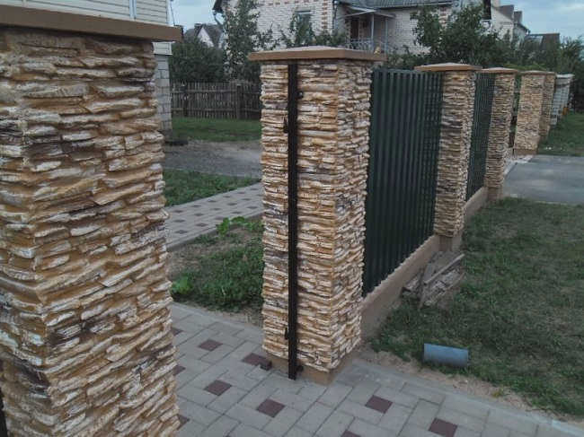 Столбики забора, облицованные камнем