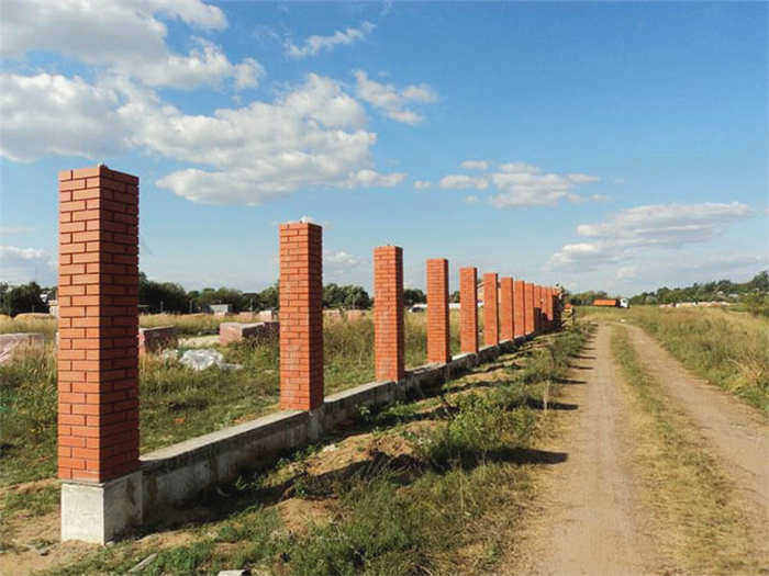 забор из гофрированного железа с кирпичными столбиками